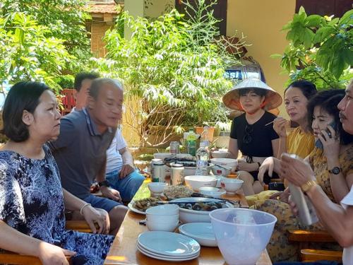 grupa ludzi siedzących przy stole jedzących jedzenie w obiekcie Mai Place Homestay w mieście Ninh Binh