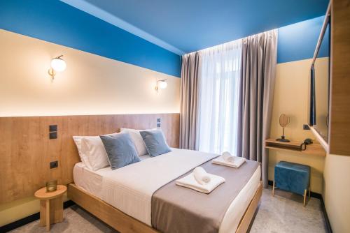 1 dormitorio con 1 cama grande, paredes azules y ventana en Metis Urbane Living Spaces en Atenas