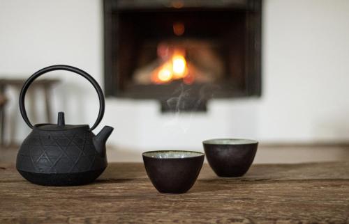a tea pot and two cups on a table with a fireplace at n o c t u r n e in Kamianets-Podilskyi