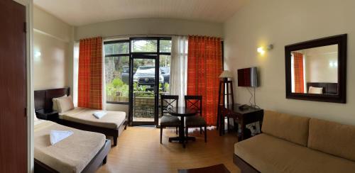 sala de estar con sofá y mesa en 3 Pax Charming Foggy Cold Breeze, Cozy Gardenville Hotel, en Baguio