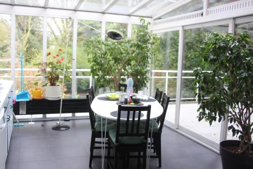 uma sala de jantar com uma mesa num jardim de Inverno em B&B Middelheim em Antuérpia