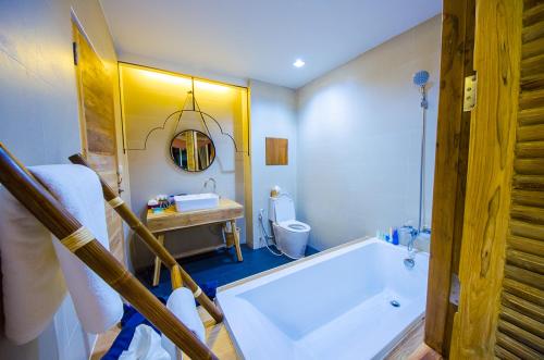 Nakorn De Sukhothai Hip Hotel في سوخوثاي: حمام مع حوض استحمام ومغسلة