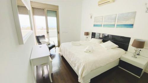 阿德赫的住宿－Villa Elisabetta, Luxury Villa with Heated Pool Ocean View in Adeje, Tenerife，一间卧室配有一张床、一张桌子、一张床和一个窗户。
