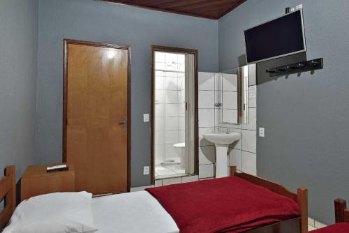 1 dormitorio con 1 cama y baño con TV. en HOTEL SENADoR, en Ribeirão Preto