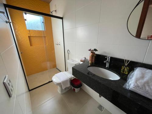 a bathroom with a sink and a shower and a toilet at Pousada Villa Recanto dos Lagos in Brumadinho