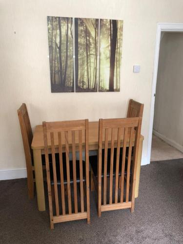 a wooden table with two chairs and a picture on the wall at 5/6 Bed House Barnsley Centre in Barnsley