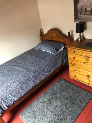 a bedroom with a bed and a wooden dresser at 5/6 Bed House Barnsley Centre in Barnsley