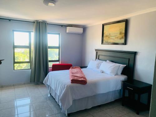 um quarto com uma cama com um cobertor vermelho em Xaba Guest Lodge em Richards Bay