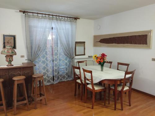a dining room with a table with chairs and a vase of flowers at Attico in Pitigliano
