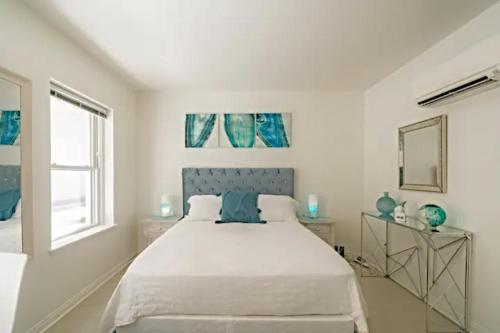een witte slaapkamer met een bed en een raam bij Beachside Apartments l Free Parking! in Los Angeles