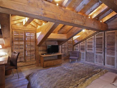 un soggiorno con soffitti in legno, una TV e una scrivania di Chalet cosy proche des pistes avec sauna et cheminée - Courchevel 1850 - FR-1-564-25 a Courchevel