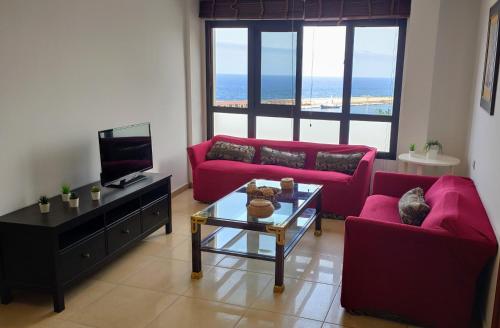 a living room with two red couches and a television at Pisos El Puerto in Santa Cruz de la Palma
