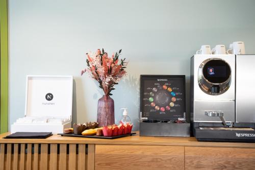 a desk with a microwave and a vase of flowers at Aiden by Best Western Clermont-Ferrand Hotel & Spa in Clermont-Ferrand