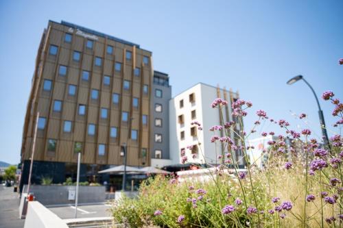 a field of flowers in front of buildings at Aiden by Best Western Clermont-Ferrand Hotel & Spa in Clermont-Ferrand