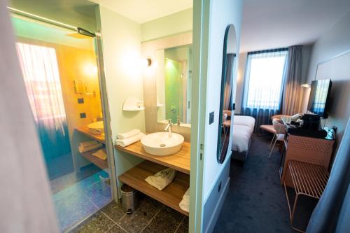 a room with a bathroom with a sink and a mirror at Aiden by Best Western Clermont-Ferrand Hotel & Spa in Clermont-Ferrand
