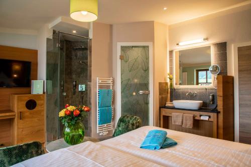 a bedroom with a bed and a bathroom with a shower at Spirit & SPA Birkenhof am Elfenhain in Grafenwiesen