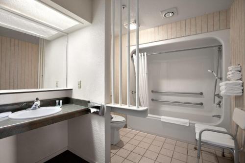La salle de bains blanche est pourvue d'un lavabo et de toilettes. dans l'établissement Travelodge by Wyndham Angels Camp CA, à Angels Camp