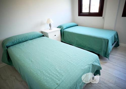 two beds in a room with green sheets at PUSHE Village Playa Granada Beach & Golf 3 in Motril