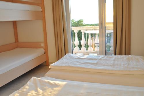 a bedroom with two bunk beds and a balcony at Seehotel Herlinde in Podersdorf am See