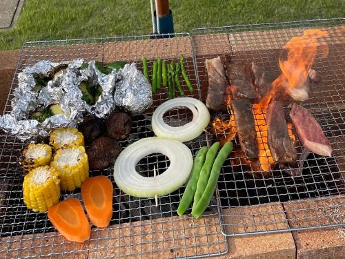 a grill with meat and vegetables on it at Holiday Villa 旅生 in Tonosho