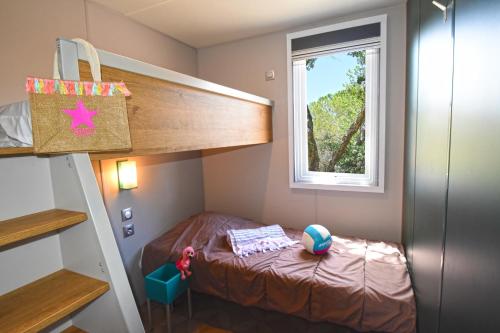 ein kleines Schlafzimmer mit einem Etagenbett und einem Fenster in der Unterkunft Camping Resort La Baume La Palmeraie in Fréjus