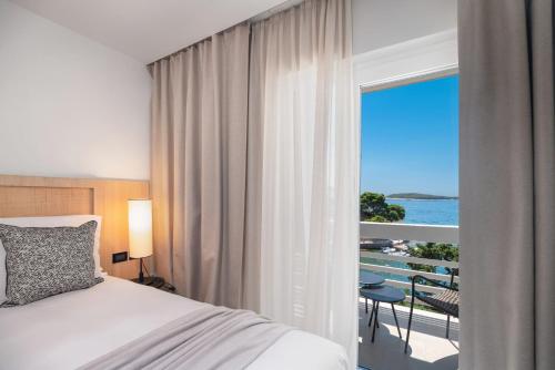 a bedroom with a bed and a view of the ocean at Beach Bay Hvar Hotel in Hvar