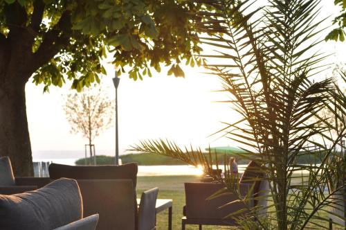 eine Terrasse mit Tischen, Stühlen und einer Palme in der Unterkunft Seehotel Herlinde in Podersdorf am See