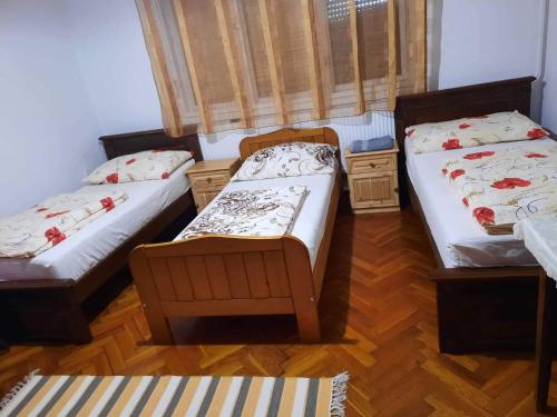two twin beds in a room with wooden floors at Farkas Szálló in Báránd