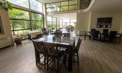 comedor con mesa, sillas y ventanas en Hotel Beaumonde Garden, en Tiflis