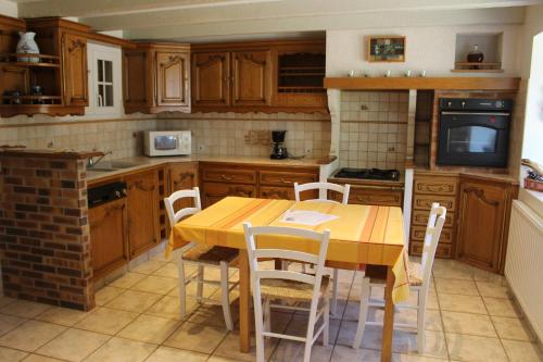 a kitchen with a wooden table and chairs at Le Clos De Lascoer in Plumergat