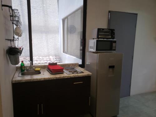 a small kitchen with a microwave and a refrigerator at Singular Coyoacán Pepper My Love! in Mexico City