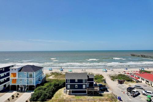 a beach with some blue houses and the ocean at Dune Alright in Oak Island