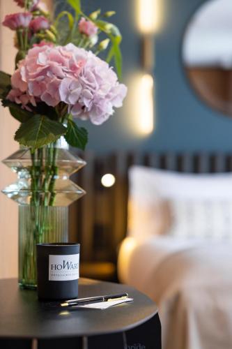 a vase of flowers on a table next to a bed at Howard sur Seine - Asnieres Paris La Defense in Asnières-sur-Seine