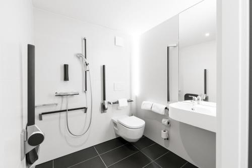 La salle de bains blanche est pourvue de toilettes et d'un lavabo. dans l'établissement B&B HOTEL Nyon, à Nyon