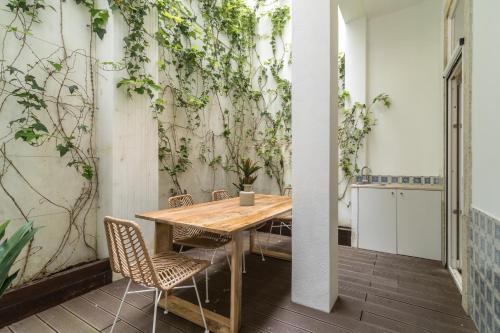 Casa Boma Lisboa - Design Apartment with Private Vegetal Terrace - Lapa VII في لشبونة: طاولة وكراسي في غرفة مع جدار مغطى بالنباتات