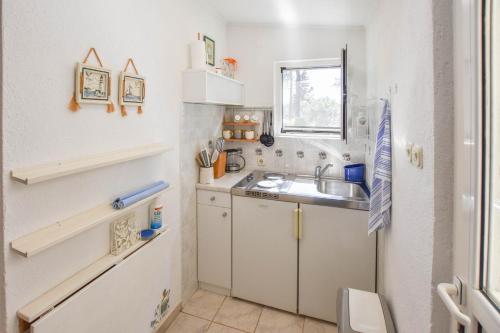 a small white kitchen with a sink and a window at Apartment Ivan in Veli Rat