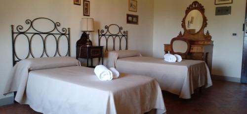 a hotel room with two beds and a table at Villa di Corliano Relais all'Ussero in San Giuliano Terme