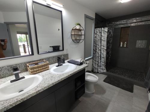 a bathroom with two sinks and a toilet and a shower at New house with comfortable king beds in Medford