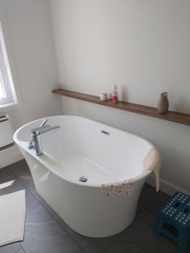 a white bath tub sitting in a bathroom at Gîte du 149 route de la Mer in Sainte-Flavie