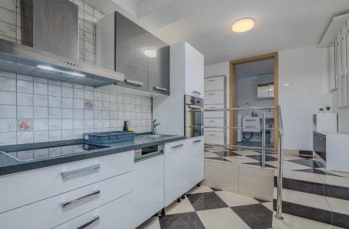 a kitchen with white cabinets and a checkered floor at Apartments Dorotea in Krk