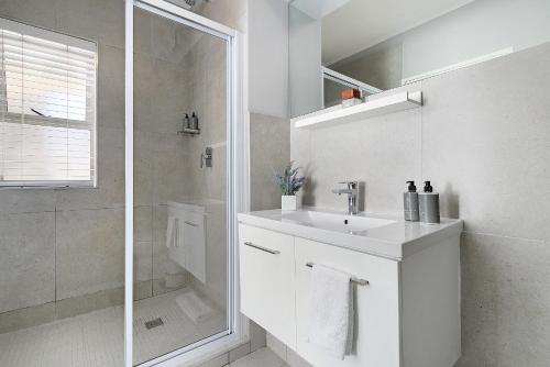a white bathroom with a sink and a shower at Century City Luxury Two Bedroom Apartment in Cape Town