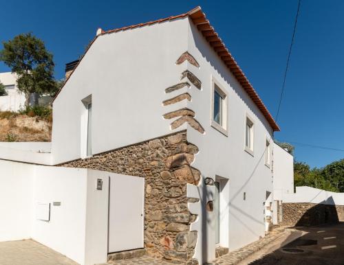 a white house with a stone wall at Beautiful House in Miranda do Corvo