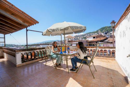 two women sitting at a table with an umbrella at Casa Colonial Taxco Centro in Taxco de Alarcón
