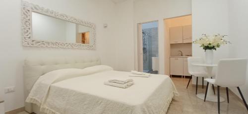 a white bedroom with a bed and a mirror at Amato Luxury Apartments in Marsala