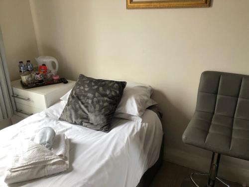 a bed with a pillow and a chair in a room at FIVEWAYS HAPPY STAYS, BRIGHTON CENTRE, Free Parking in Brighton & Hove