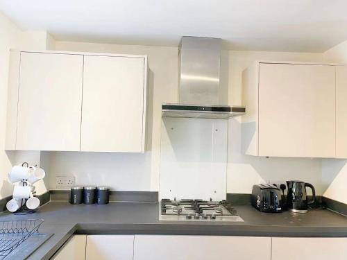 a kitchen with white cabinets and a stove top oven at Oxford City Centre House With Parking in Oxford