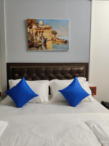ein Bett mit blauen Kissen und ein Bild darüber in der Unterkunft Regina's Place in Mandrem