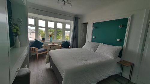 een slaapkamer met een groot bed met een groene muur bij Orient B&B in Holyhead