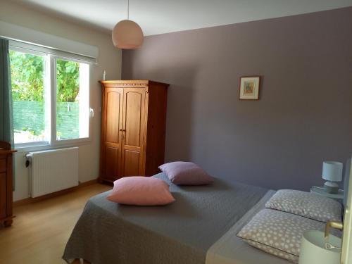 1 dormitorio con 1 cama con 2 almohadas rosas en Le jardin d'Anatole en Bourges