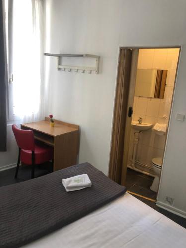 パリにあるホテル コージー モンソーのベッド、テーブル、バスルームが備わる客室です。
